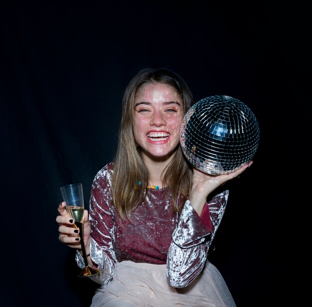 Mujer feliz sentada con bola de discoteca en la mano