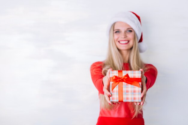 Mujer feliz en el sombrero de santa con caja de regalo pequeña