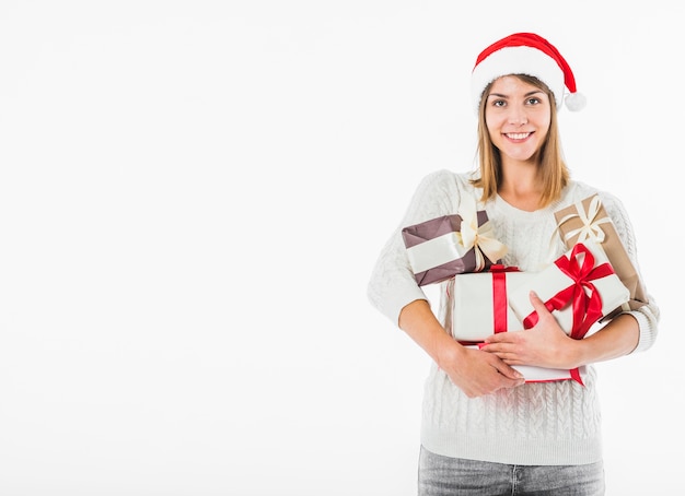 Mujer feliz en el sombrero de santa con cajas de regalo