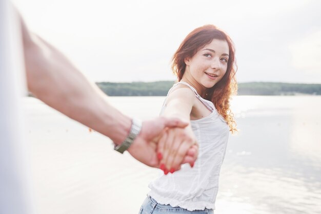 Una mujer feliz sonriente con una expresión juguetona y una mano con su marido.