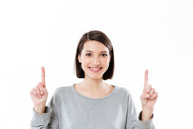 Mujer feliz sonriente que señala dos dedos hacia arriba en el espacio de la copia