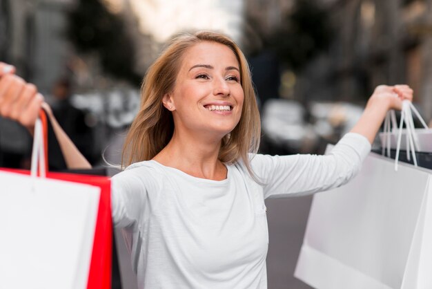 Mujer feliz sosteniendo bolsas de la compra después de la sesión de compras de venta