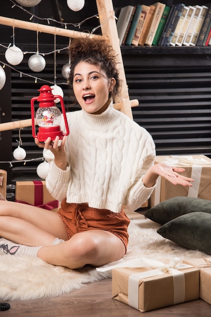 Mujer feliz sosteniendo una lámpara de Navidad roja