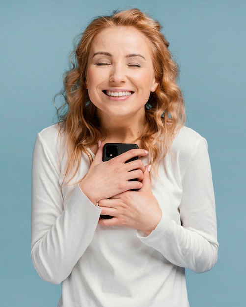 Foto gratuita mujer feliz sosteniendo en el móvil