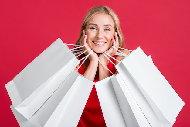 Mujer feliz sosteniendo muchas bolsas de la compra después de ir de compras