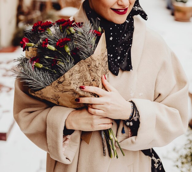 Mujer feliz sosteniendo un ramo de flores en invierno