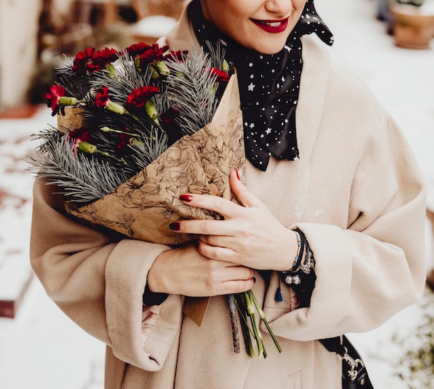 Mujer feliz sosteniendo un ramo de flores en invierno