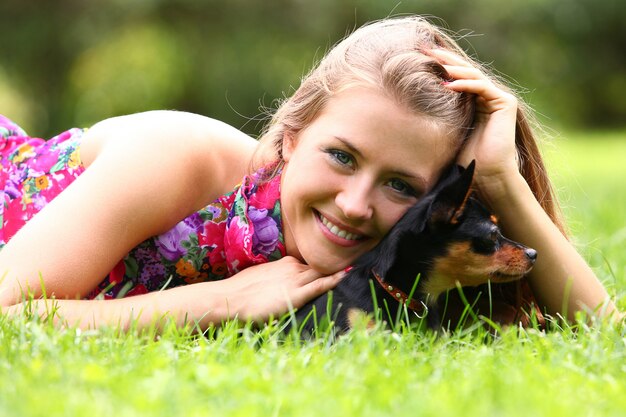 Mujer feliz y su lindo perro en la hierba