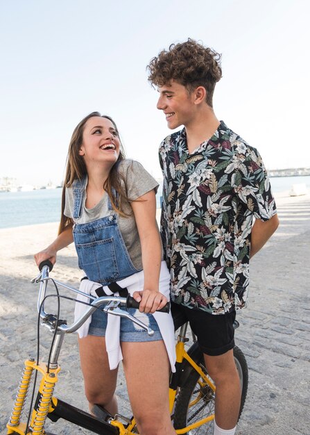 Mujer feliz con su novio montando bicicleta en el puerto