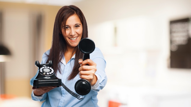 Mujer feliz sujetando un teléfono con dial giratorio