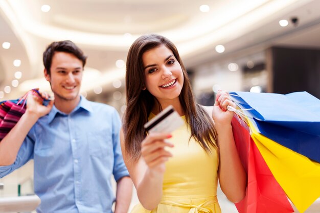 Mujer feliz con tarjeta de crédito y bolsas de compras