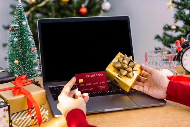 Mujer feliz con tarjeta de crédito haciendo compras online presentes en Navidad