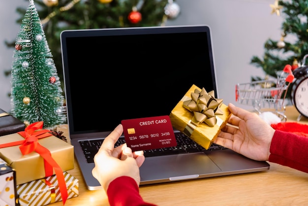 Mujer feliz con tarjeta de crédito haciendo compras online presentes en Navidad