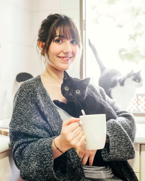 Foto gratuita mujer feliz con una taza de café con su gato