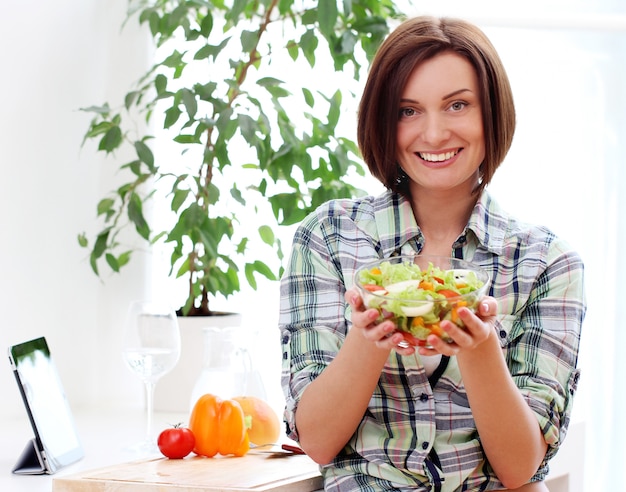 Mujer feliz con tazón de ensalada fresca