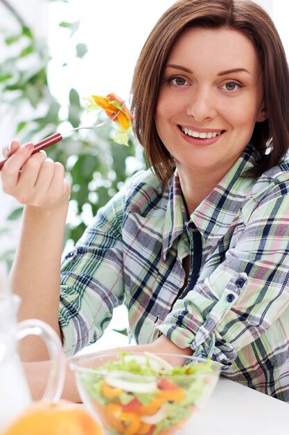 Mujer feliz con tazón de ensalada fresca