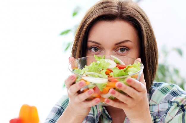 Mujer feliz con tazón de ensalada fresca