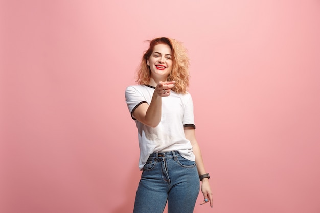 La mujer feliz te señala y te quiere, retrato de detalle de media longitud en la pared de color rosa.