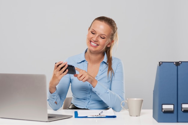 Mujer feliz con teléfono móvil durante el trabajo de oficina