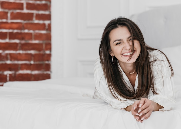 Mujer feliz de tiro completo en la cama