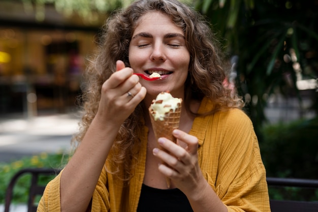 Mujer feliz de tiro medio comiendo helado