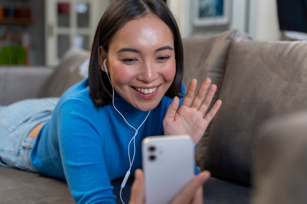 Mujer feliz de tiro medio con teléfono en casa