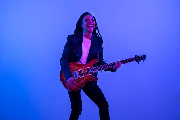 Mujer feliz tocando la vista lateral de la guitarra