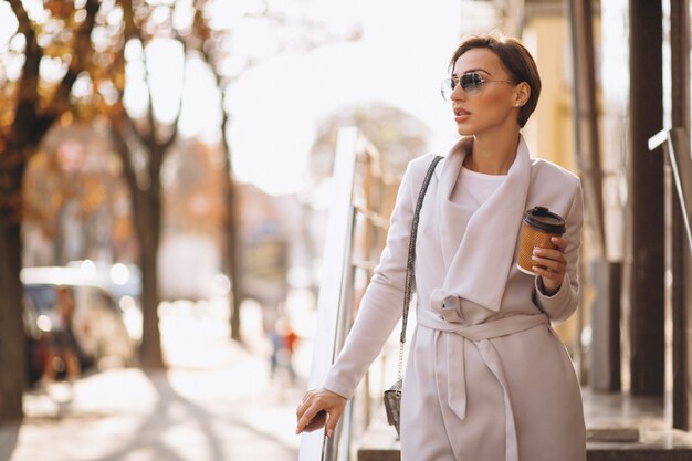 Mujer feliz, tomando café en la calle.