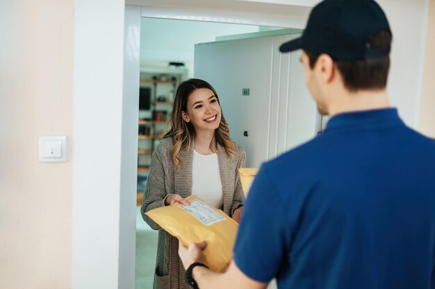 Mujer feliz tomando el paquete de un mensajero mientras recibe la entrega a domicilio