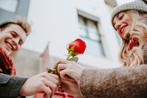 Mujer feliz tomando rosa del hombre