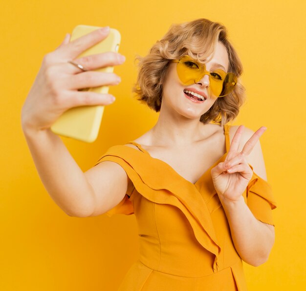 Mujer feliz tomando un selfie mientras usa gafas de sol