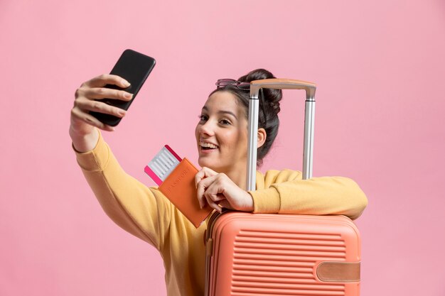 Mujer feliz tomando una selfie con su pasaporte y equipaje