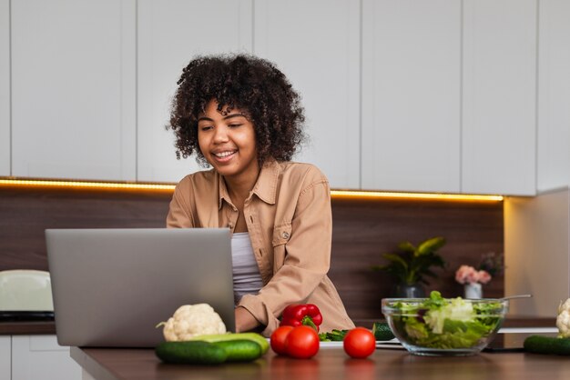 Mujer feliz trabajando en la computadora portátil en la cocina