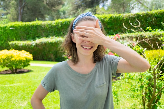 Mujer feliz en traje de verano que cubre los ojos del sol