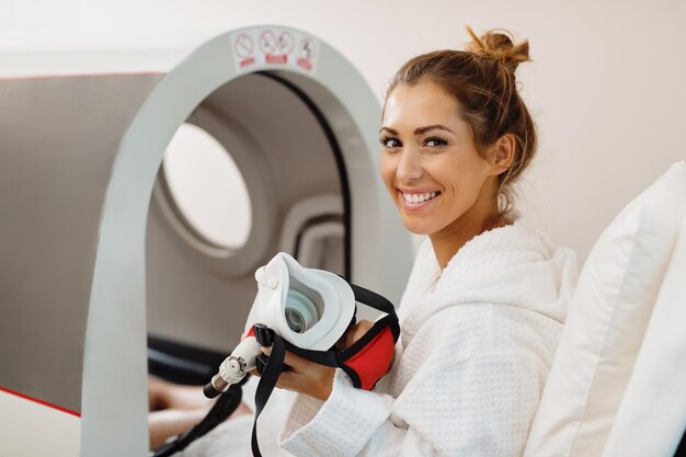 Mujer feliz con tratamiento de oxígeno en cámara hiperbárica en el spa de salud