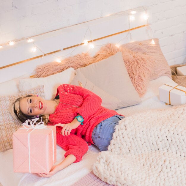 Mujer feliz tumbada en cama en navidad