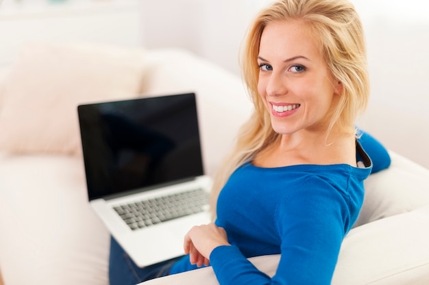 Mujer feliz usando laptop en casa