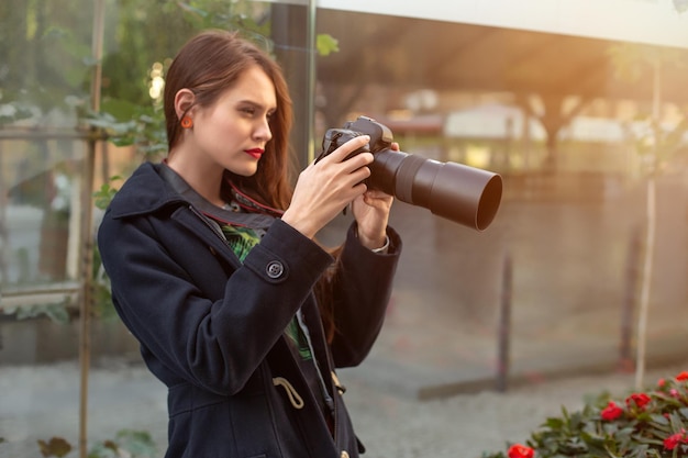 Mujer feliz de vacaciones fotografiando con cámara en la calle de la ciudad. Divertirse en la ciudad con cámara, foto de viaje del fotógrafo.