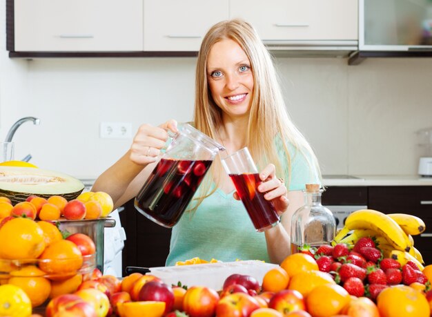 Mujer feliz vertiendo bebidas con frutas