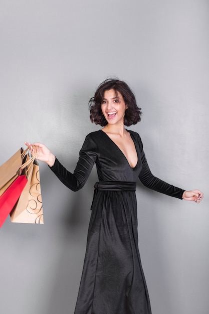 Mujer feliz en vestido negro con bolsas de compras