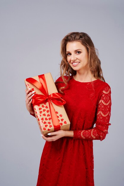 Mujer feliz en vestido rojo sosteniendo un regalo