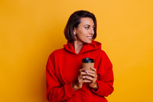 Mujer feliz vistiendo ropa de abrigo de invierno se calienta con una taza de café caliente