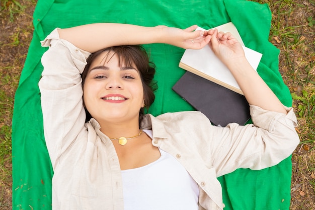 Foto gratuita mujer femenina alegre que miente en prado verde