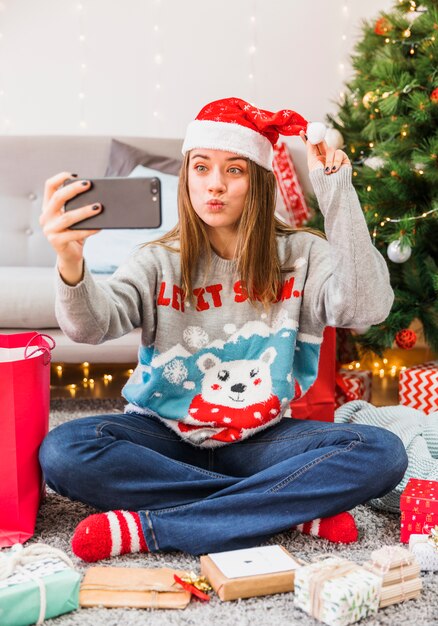 Mujer festiva haciendo pucheros en los labios mientras toma selfie