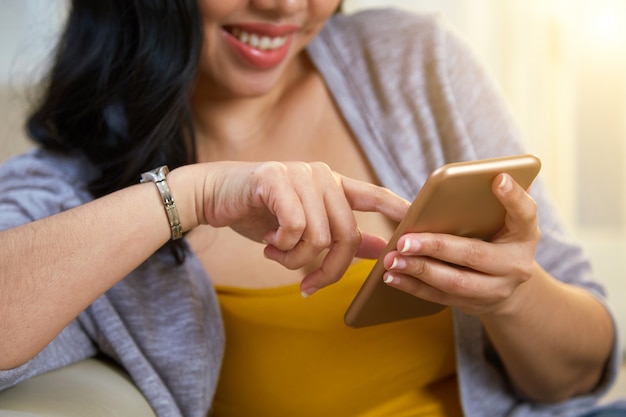 Mujer filipina anónima navegando por teléfono inteligente