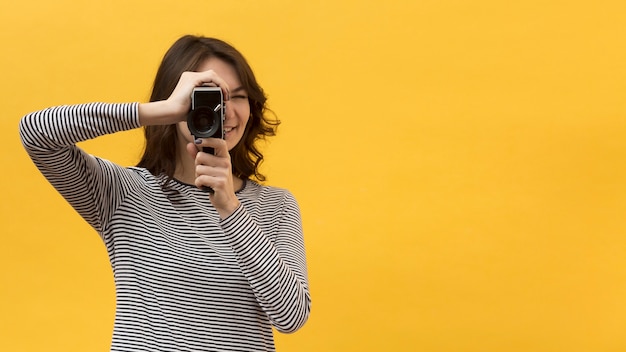 Mujer filmando con una cámara retro con espacio de copia