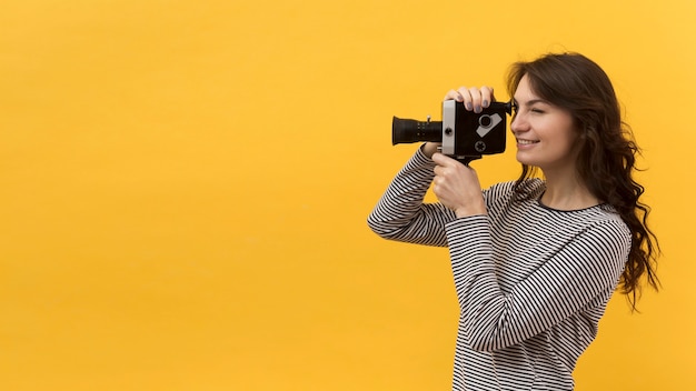 Foto gratuita mujer filmando con una cámara retro