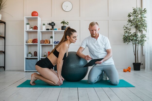 Mujer con fisioterapeuta haciendo ejercicios con pelota