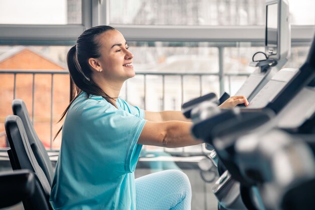Mujer de fitness en bicicleta haciendo ejercicio cardiovascular en el gimnasio