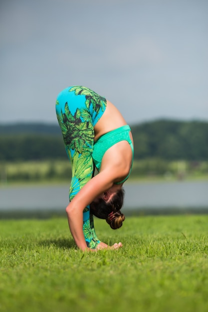 Mujer fitness haciendo ejercicio de yoga y relajarse con ropa deportiva en el parque verde en verano